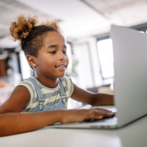 African kid girl spending time with notebook and modern technology