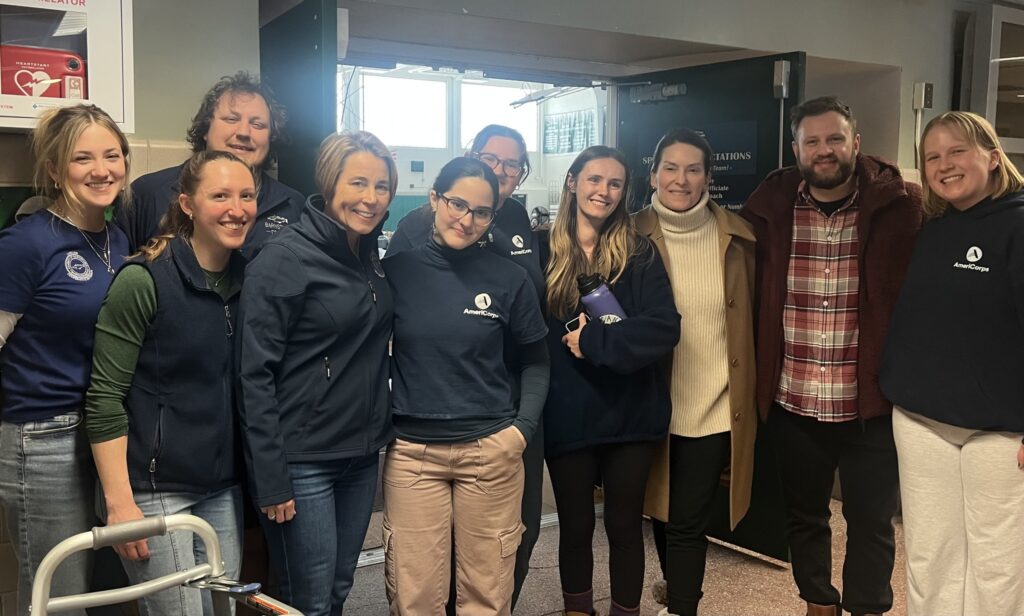 Governor Maura Healey and Senator Julian Cyr pose with AmeriCorps Cape Cod members currently staffing the Dennis-Yarmouth Regional Shelter, supporting residents impacted by widespread power outages.