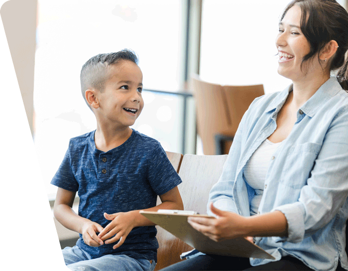 child smiling with adult sitting on a couch laughing